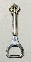 Close-up front view of vintage sterling silver bottle opener showing detailed floral and scroll design on handle.