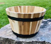 Side view of the acacia wood barrel planter showing natural wood slats and metal bands