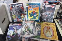 Comic book covers including Superman, Spider-Man, and multiple Bloodshot issues arranged on a table.