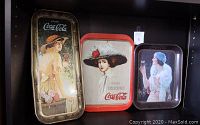 Photo of three vintage Coca Cola metal trays with women in vintage attire, showing overall condition and artwork.