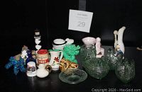 Photo showing a collection of assorted miniature items made from glass, porcelain, and ceramics in various colors, arranged on a black surface.