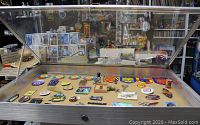 Display case, open with collectible patches, pins, badges, and small items inside