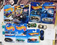 Array of 11 Hot Wheels cars, 7 still in packaging and 4 loose vintage models visible on table.