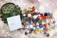 Green glass hobnail jar and marbles displayed spilled out onto a plastic sheet