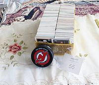 Box and pile of over 1,000 hockey trading cards with various players and designs, loosely organized, situated on a floral tablecloth.