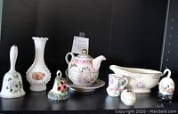 Photo showing porcelain tea-for-one set, milk glass floral vase, porcelain gravy bowl, decorative eggs and porcelain bell.