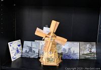 Full view of the wooden musical windmill savings bank displayed with five ceramic windmill-themed decorative hot plates in the background.