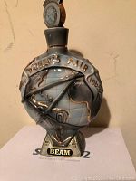 Front view of the 1965 World's Fair Jim Beam decanter shaped as a globe with gold markings and blue glaze.
