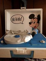 Front photo of the Mickey Mouse record player inside its case with tonearm, microphone and power cord visible.