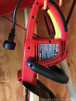Side view of the Black and Decker electric hedge trimmer showing the handle with yellow trigger and power cord.