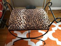 Top down view showing animal print cushion and curved black metal armrests.