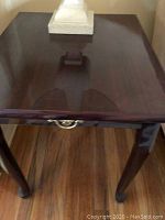 Photo of the polished cherry finish surface and front edge with metal handle of one end table.