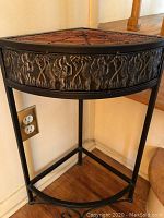 Full view of the Asian corner table, showing black metal frame, carved elephant motif on the semicircular front panel, and bamboo slat top.