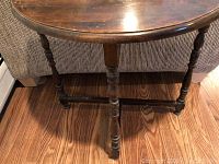 Front view of demilune wood table showing wood top and turned legs with stretcher base.