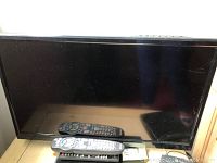 Front view of the 24-inch Element Electronics LED TV with two remote controls placed in front.