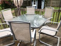 Full set on wood deck showing hexagonal glass top table and six chairs