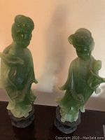 Two full-view jade statues side by side on a table