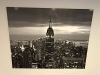 Large black and white New York City skyline wall art showing Empire State Building prominently in center at dusk or night.