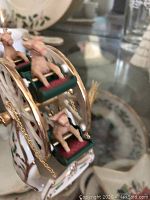 Close-up of Lenox holiday Ferris wheel figurine, showing detailed painted reindeer figures on seats and gold trim with holly decoration on base.