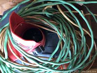 Close-up of red chute and thick green electric cord coiled on snowthrower.