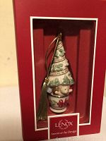 Front of the ornament inside red Lenox American by Design box, showing porcelain Christmas tree with bear and gold tassel.