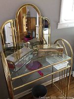 Vanity table viewed from the front showing mirrored table top and decorative mirrored boxes placed on it.