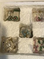 Top view of original Styrofoam box containing 5 assorted Lenox Christmas ornaments wrapped in plastic, showing a white train, a horse, and other holiday-themed designs.