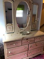 Full dresser with attached triple mirror showing overall design and condition including floral details and knobs