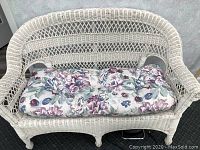 Front view of white wicker loveseat with floral cushion