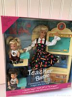 Front view of Teacher Barbie doll in original box, showing the doll dressed in school teacher outfit with two small children dolls and classroom themed backdrop.