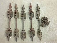 Five antique metal fence pieces laid out on concrete floor, showing front view and overall size.