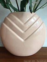 Full view of smaller peach colored ceramic vase showing embossed curved chevron-like lines.