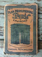 Front cover of stapled booklet titled “Plan Monumental Paris & Environs Itinéraire Métropolitain,” illustration of Arc de Triomphe in green on tan paper