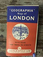 Front cover of the 'Geographia' London map booklet with orange and blue cover and white text.