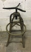 Full view of antique wooden stool base with metal adjustable screw mechanism.