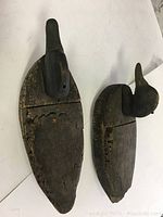 Photo showing top view of two weathered wooden duck decoys exhibiting cracking and wood rot.