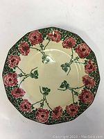 Top view showing the full face of the plate with pink floral border and green leaf patterns in the center.