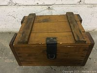 Front view of the solid wood box showing metal latch and wood reinforcement on lid.