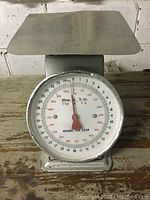 Front view of the vintage weigh scale showing the round dial marked with ounces, grams, and kilograms.