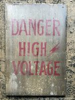 Full view of the rectangular wooden 'Danger High Voltage' sign showing faded red text and weathered surface.