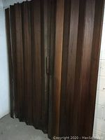 Front view showing folded vintage rosewood bifold doors with rich brown wood grain and paneling