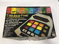 Original boxed Fabulous Fred 1980 electronic handheld game with color buttons and graphic icons of 10 games on the box front.