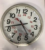 Front view of vintage Westclox electric wall clock showing full clock face, black 12-hour numbers, red 24-hour numbers, black hour and minute hands, red second hand, silver metallic frame.