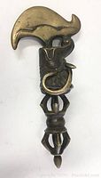 Full view of vintage brass metal scraper showing curved, somewhat sharp blade, snake figure coiled around ornate handle