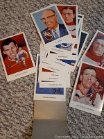 Photo showing a spread of hockey hall of fame cards in mint condition featuring portraits and player action shots on a grey carpet background.