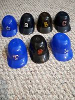 Seven mini baseball helmets on carpet showing team logos and colors