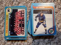 Top view of stacked hockey cards showing Philadelphia Flyers team card and St. Louis Blues player card.