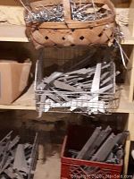 Basket and wire basket holding various metal brackets and hooks on wooden shelving