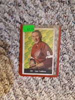 Front image of the Leo Labine hockey card showing the player in red team jersey with a green background pattern and the Detroit Red Wings logo.