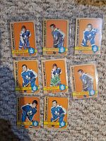 Front view of eight 1972-73 Topps Toronto Maple Leafs hockey cards: Jim McKenny (two cards), Paul Henderson (two cards), Bob Baun (two cards), Ron Ellis (two cards). Cards laid flat on carpet surface.